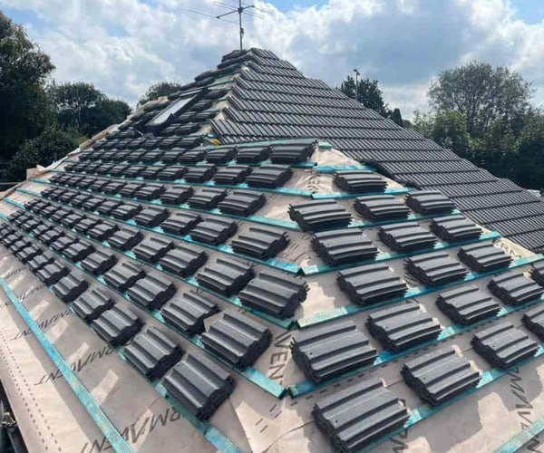 This is a photo of a new hip roof being installed. New felt, battens, and grey tiles have been installed, also a new velux window. Works carried out by ATY Roofing Mexborough