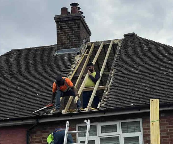 This is a photo of a roof repair being carried out. A section of the roof has been stripped and two roofers are replacing the rafters. Works being carried out by ATY Roofing Mexborough